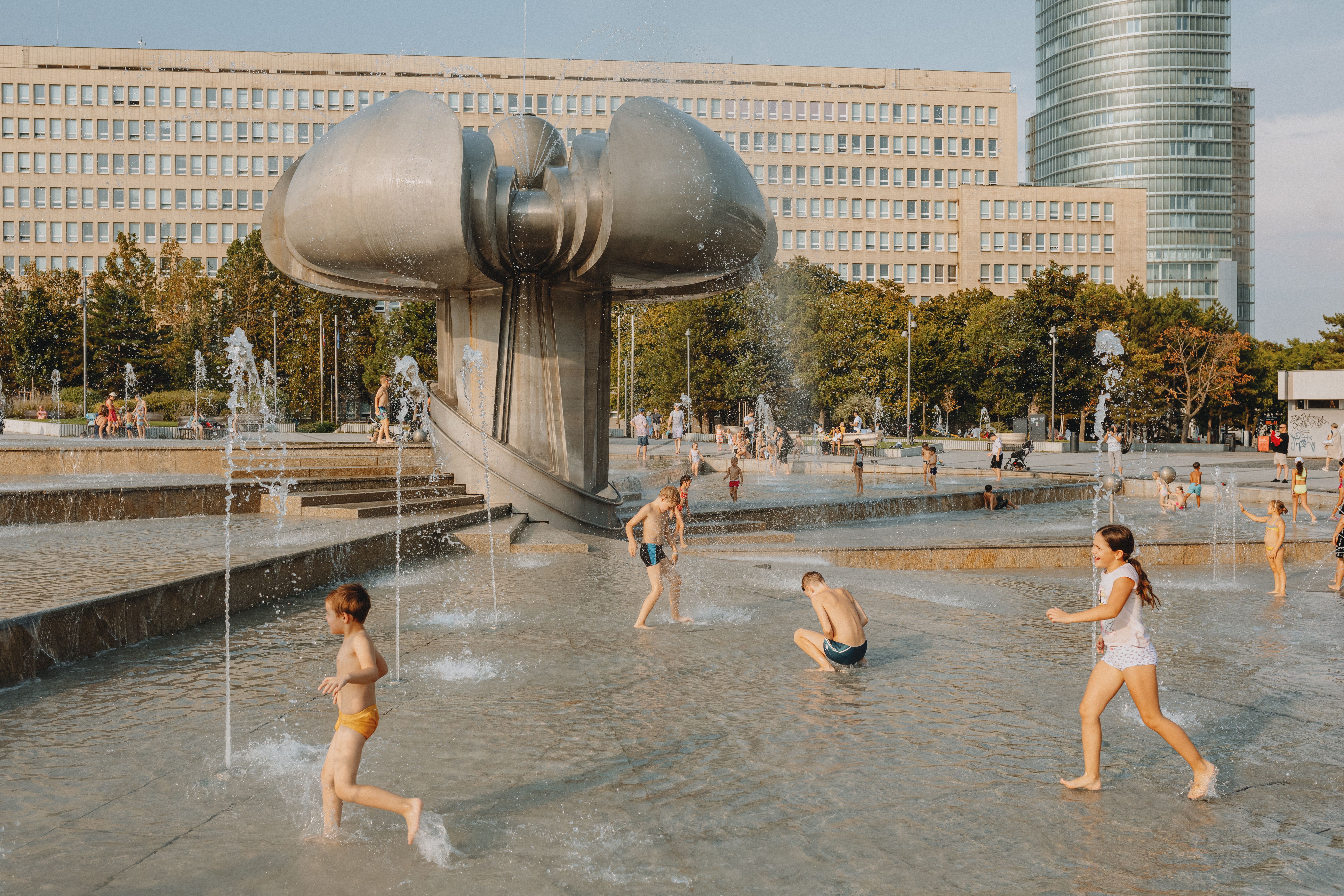 Children enjoying a sunny day playing at a modern urban fountain park. — Trójmiasto