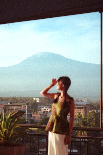 Young woman on a balcony admiring the stunning view of Mount Kilimanjaro at sunset.