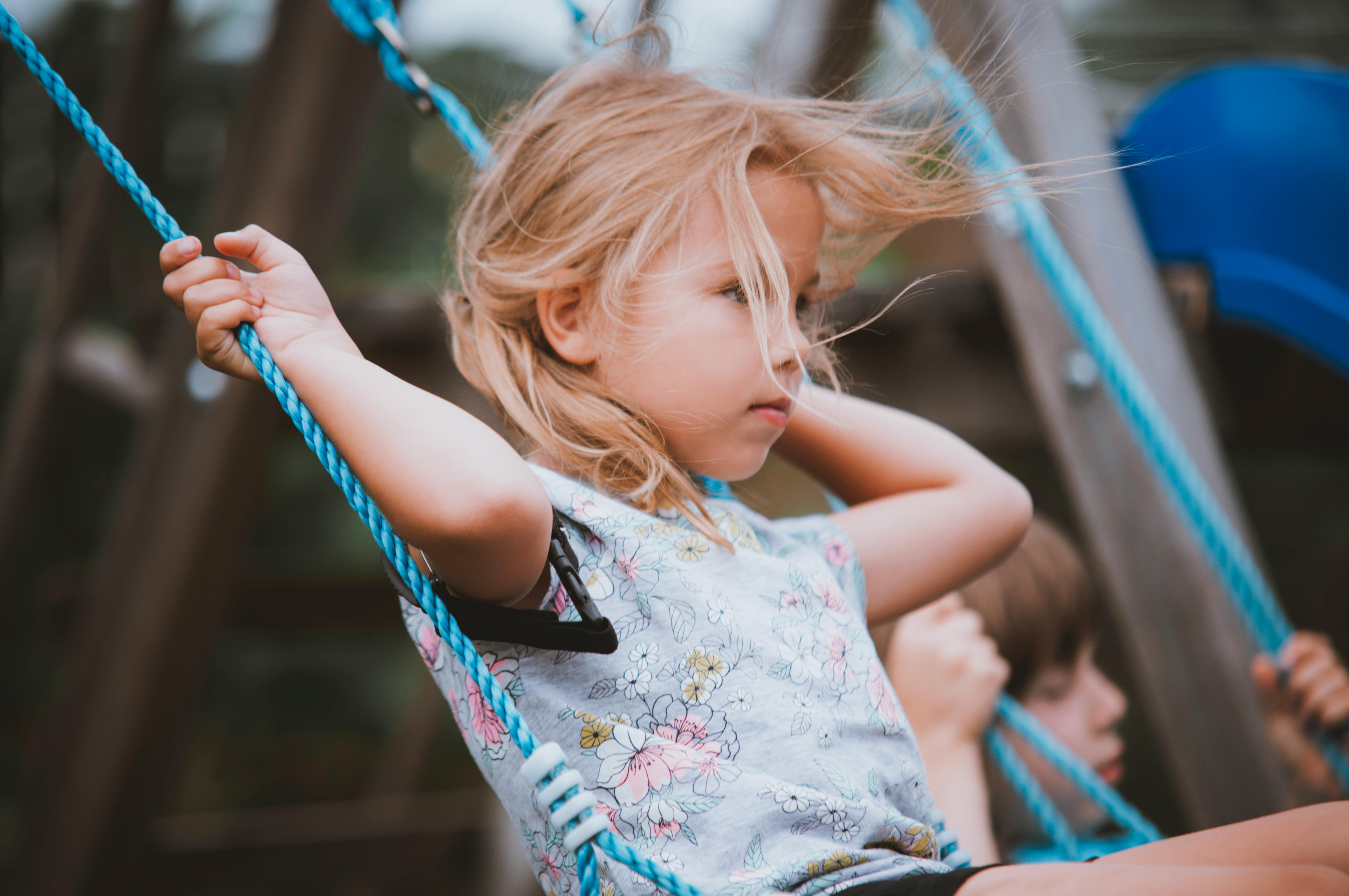 a little girl on a swing with her hair blowing in the wind