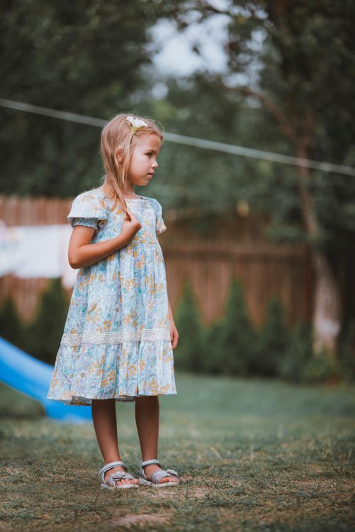A little girl standing in the grass wearing a dress Free Stock Photo A little girl standing in the grass wearing a dress Free Stock Photo