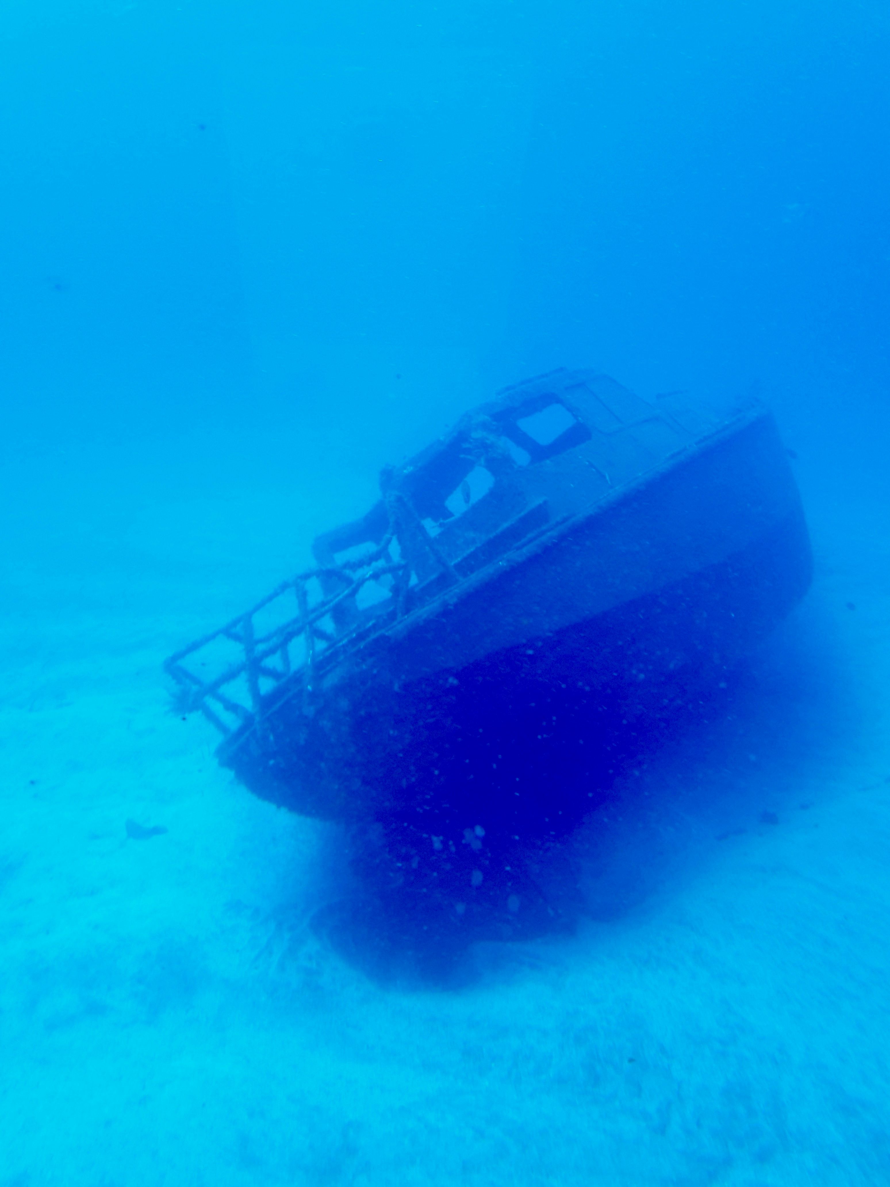 Een gezonken schip dat op de oceaanbodem rust, omringd door helder turquoise water.