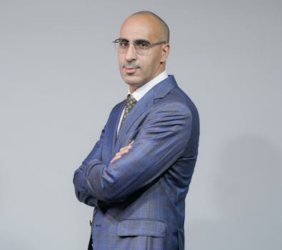 Confident businessman in blue suit posing in studio with arms crossed.