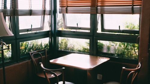 Free Sunlit dining corner with classic chairs and wooden blinds for a warm and inviting atmosphere. Stock Photo