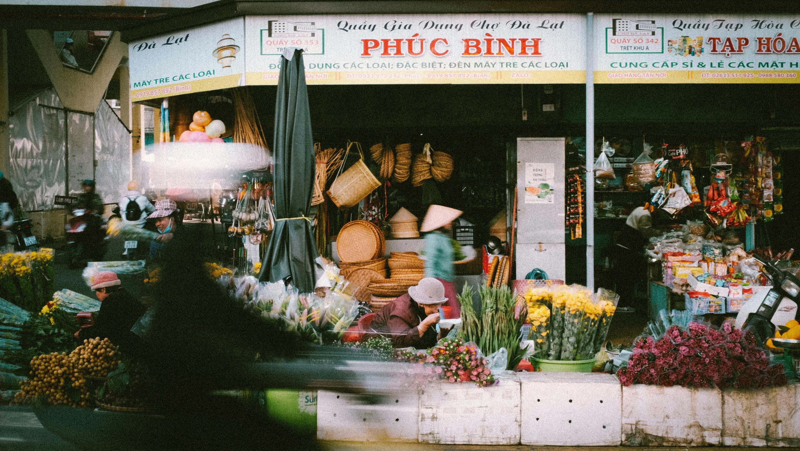 a blurry photo of a flower shop with a man on a bike