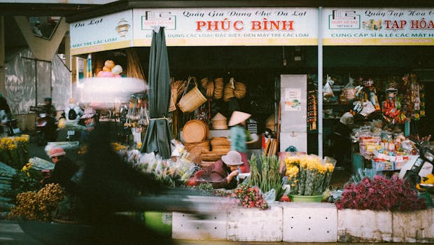 A bustling street market with colorful flowers and local vendors selling products in Da Lat.
