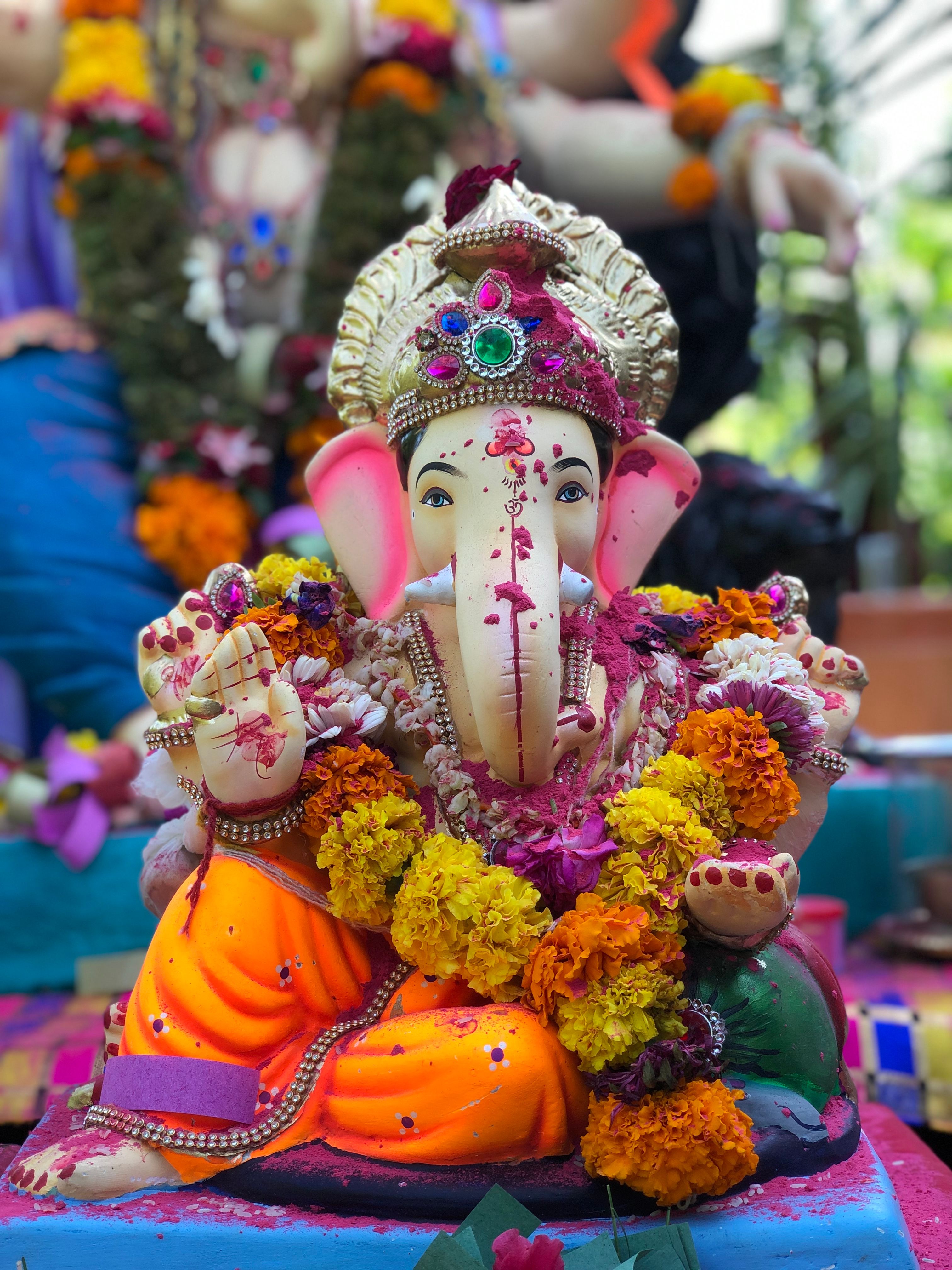 Colorful Ganesh idol with flowers during a traditional Indian festival in Eru, India.