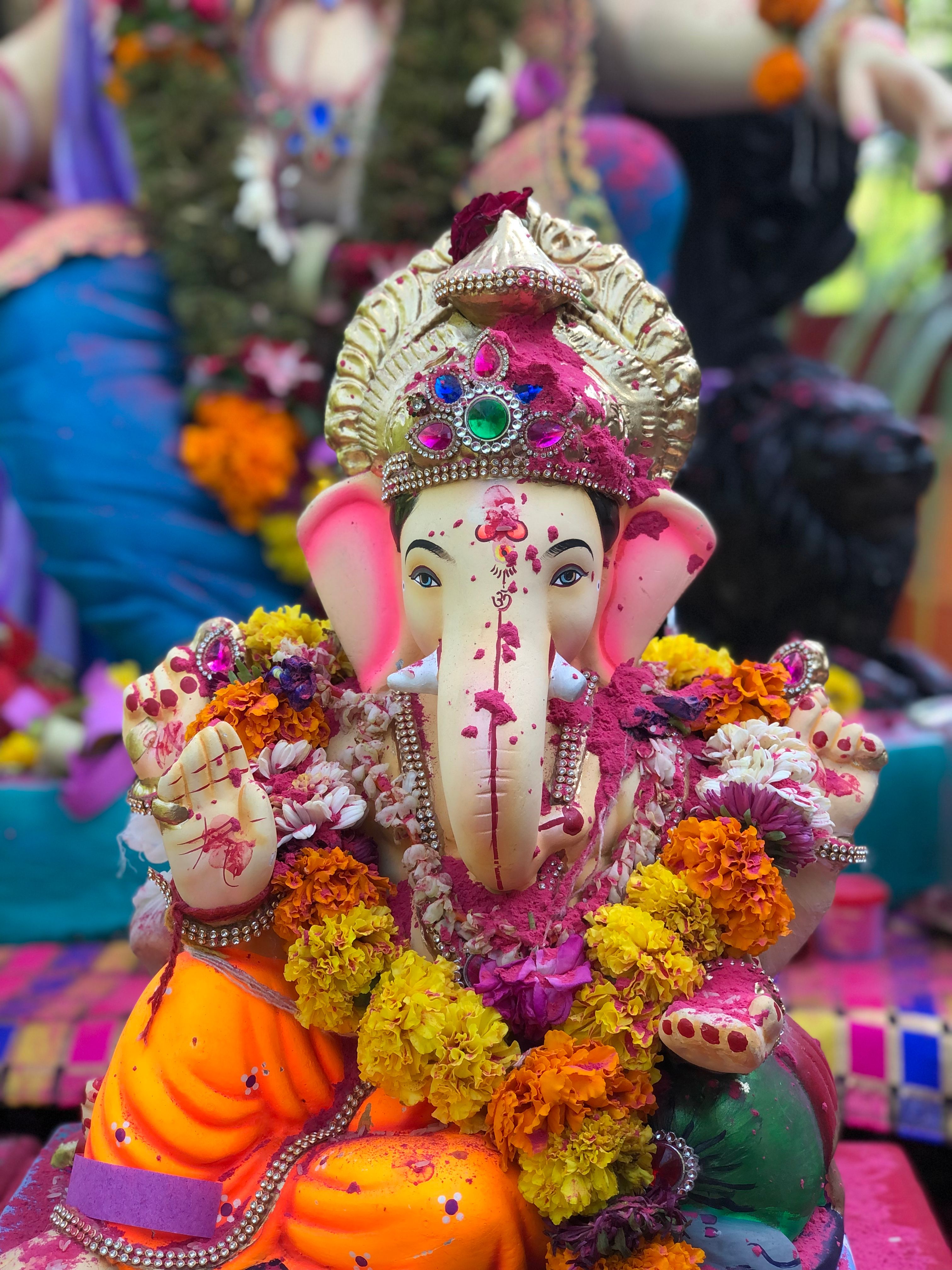 Colorful statue of Lord Ganesh adorned with marigolds during an outdoor festival.
