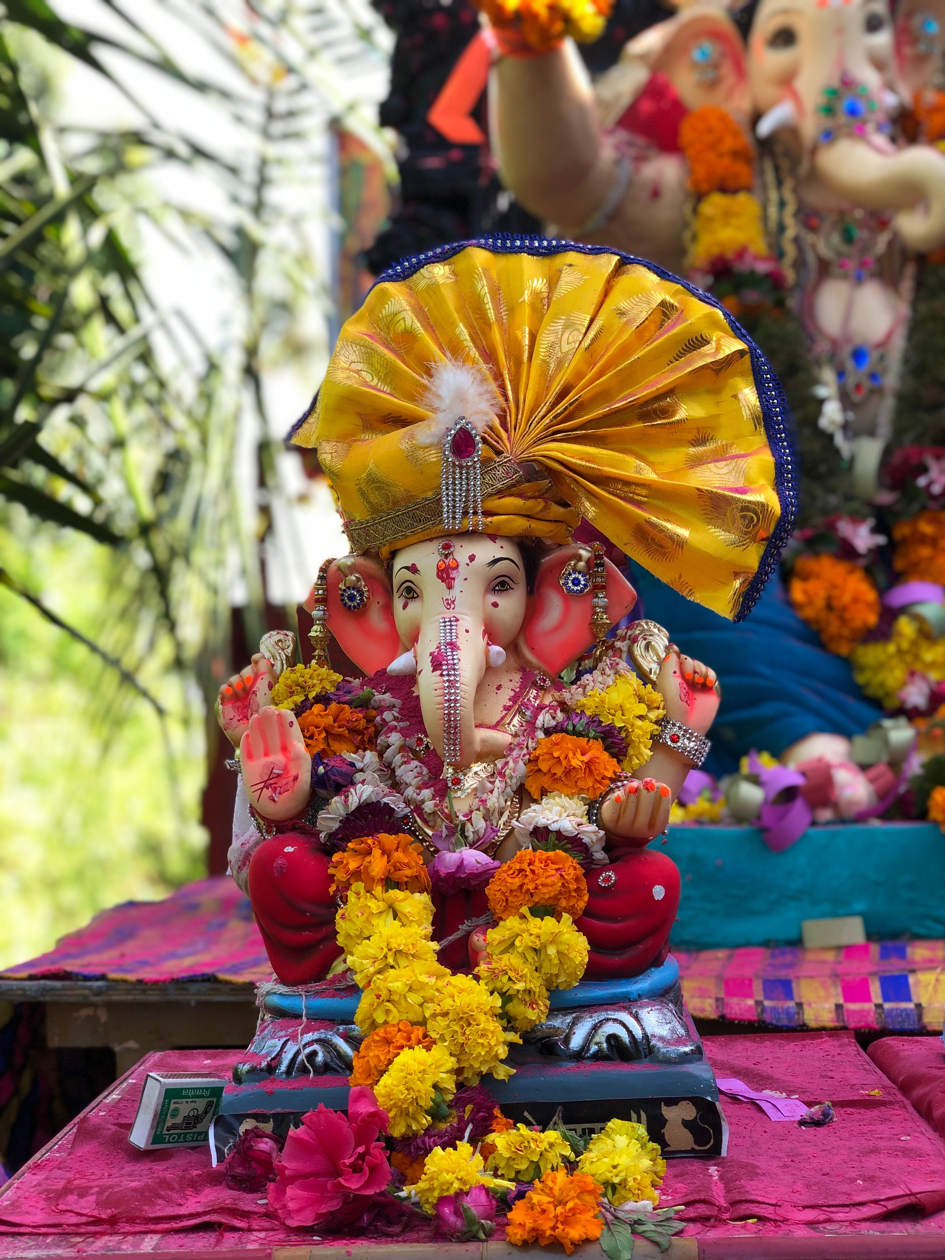 Colorful statue of Lord Ganesh decorated with flowers, highlighting Indian religious tradition.