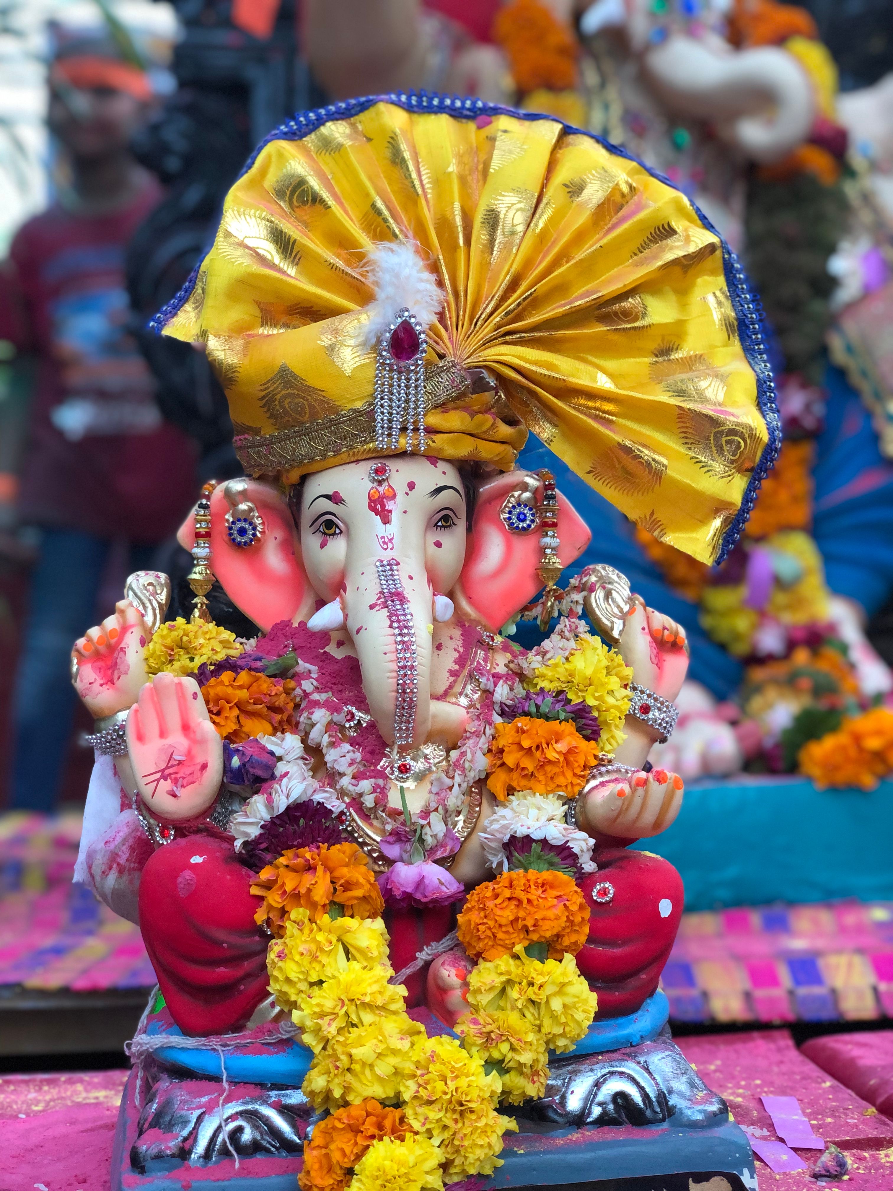 Colorful Ganesh idol decorated with flowers at a traditional Indian festival.