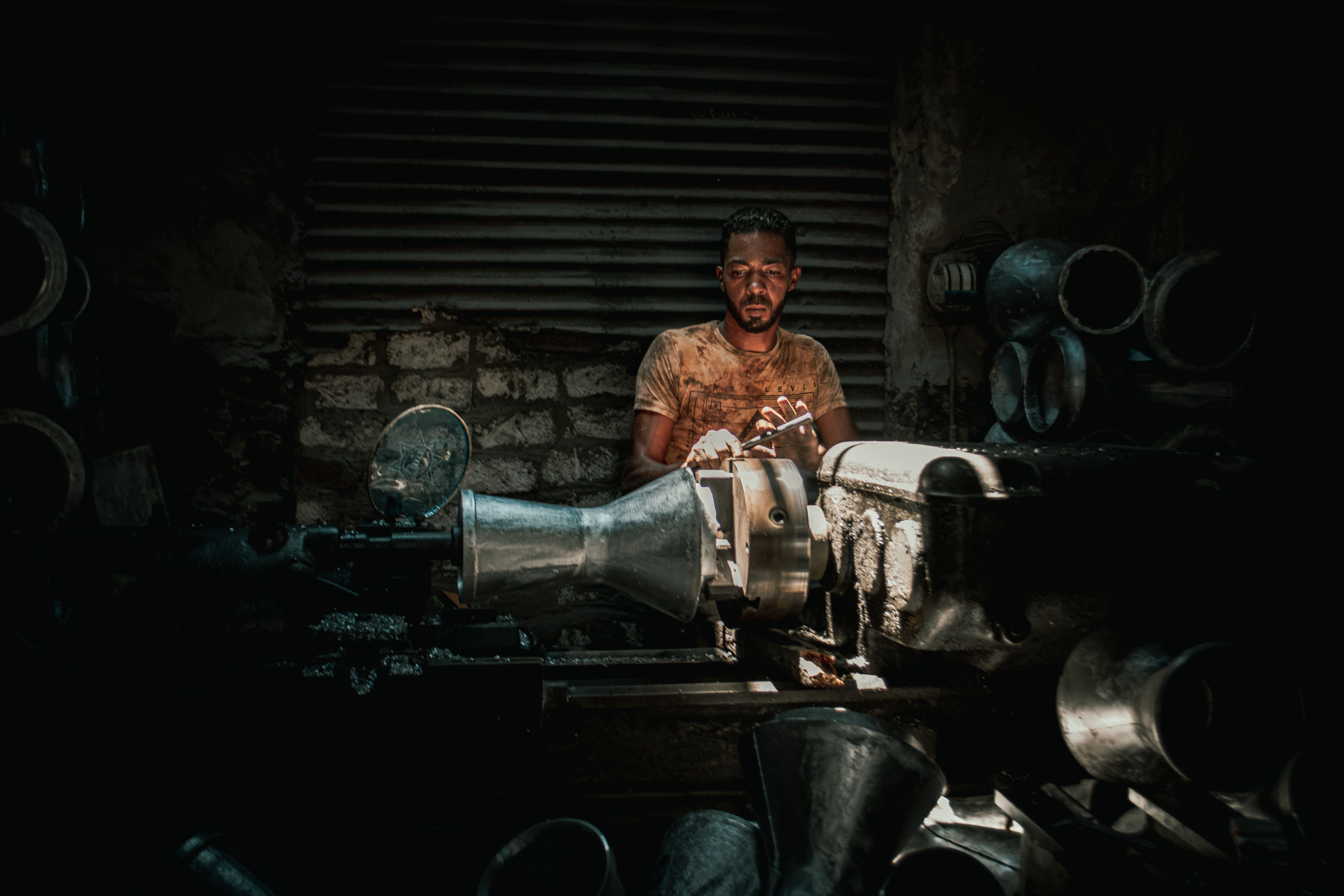 Portrait of a man in a dimly lit industrial setting operating heavy machinery.