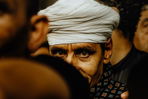 Free Close-up of a man wearing a turban, capturing an intense gaze in a crowded setting. Stock Photo