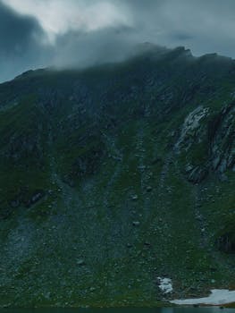 薄雾笼罩的山峰，绿树成荫，地形崎岖，景色宁静