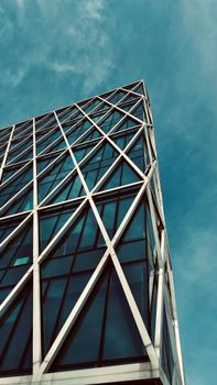 Modern skyscraper with geometric design and glass facade under clear blue sky.