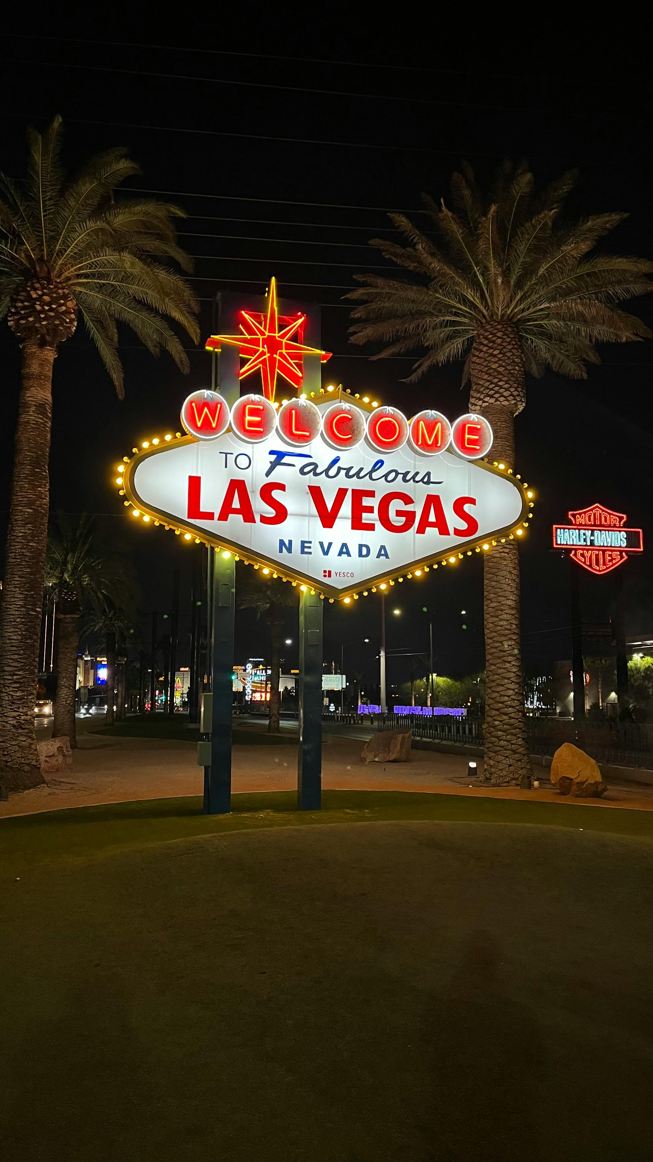 Famous Welcome to Las Vegas sign illuminated at night amidst palm trees.