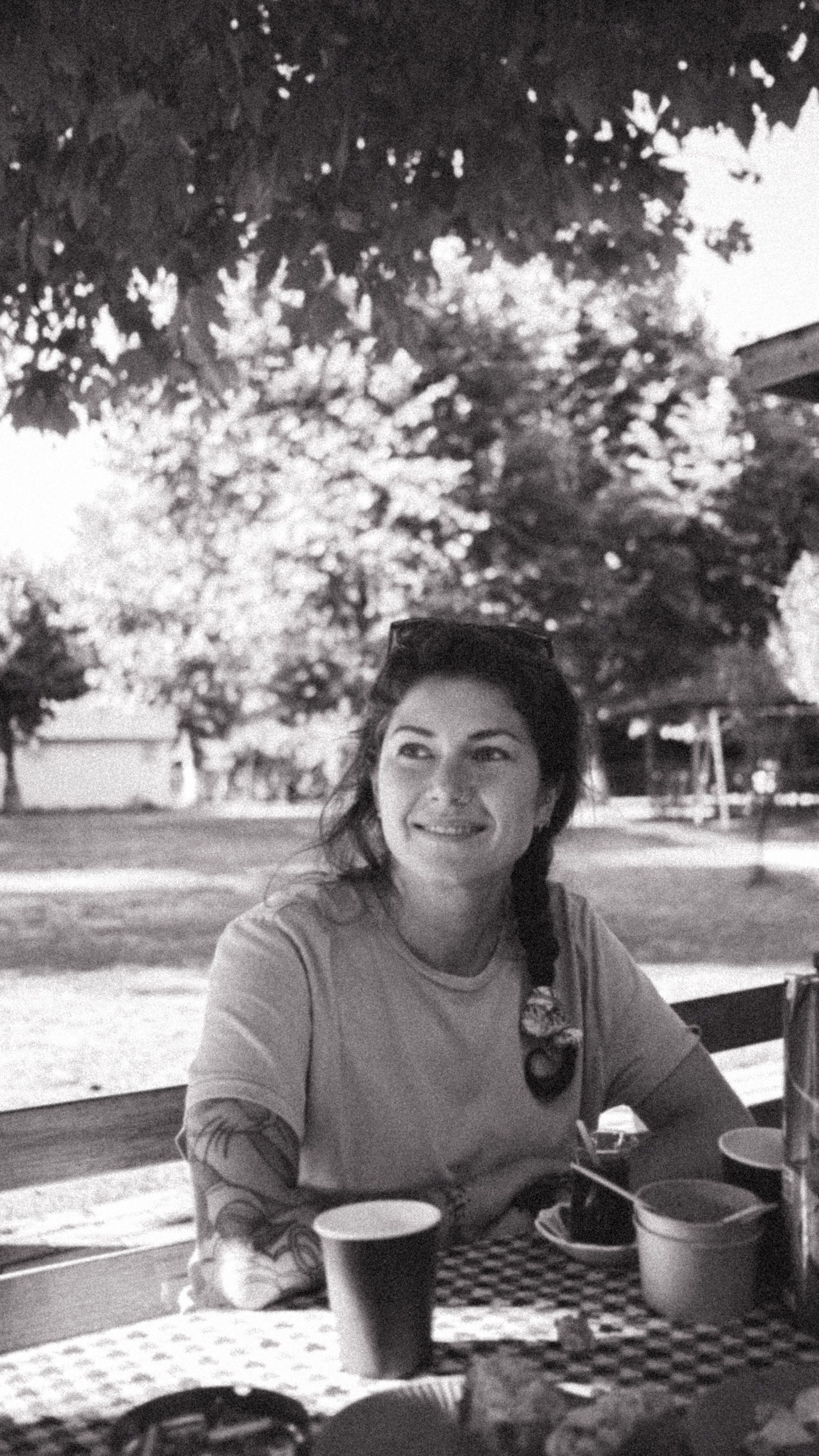 Smiling woman enjoys a relaxed outdoor picnic on a sunny day.