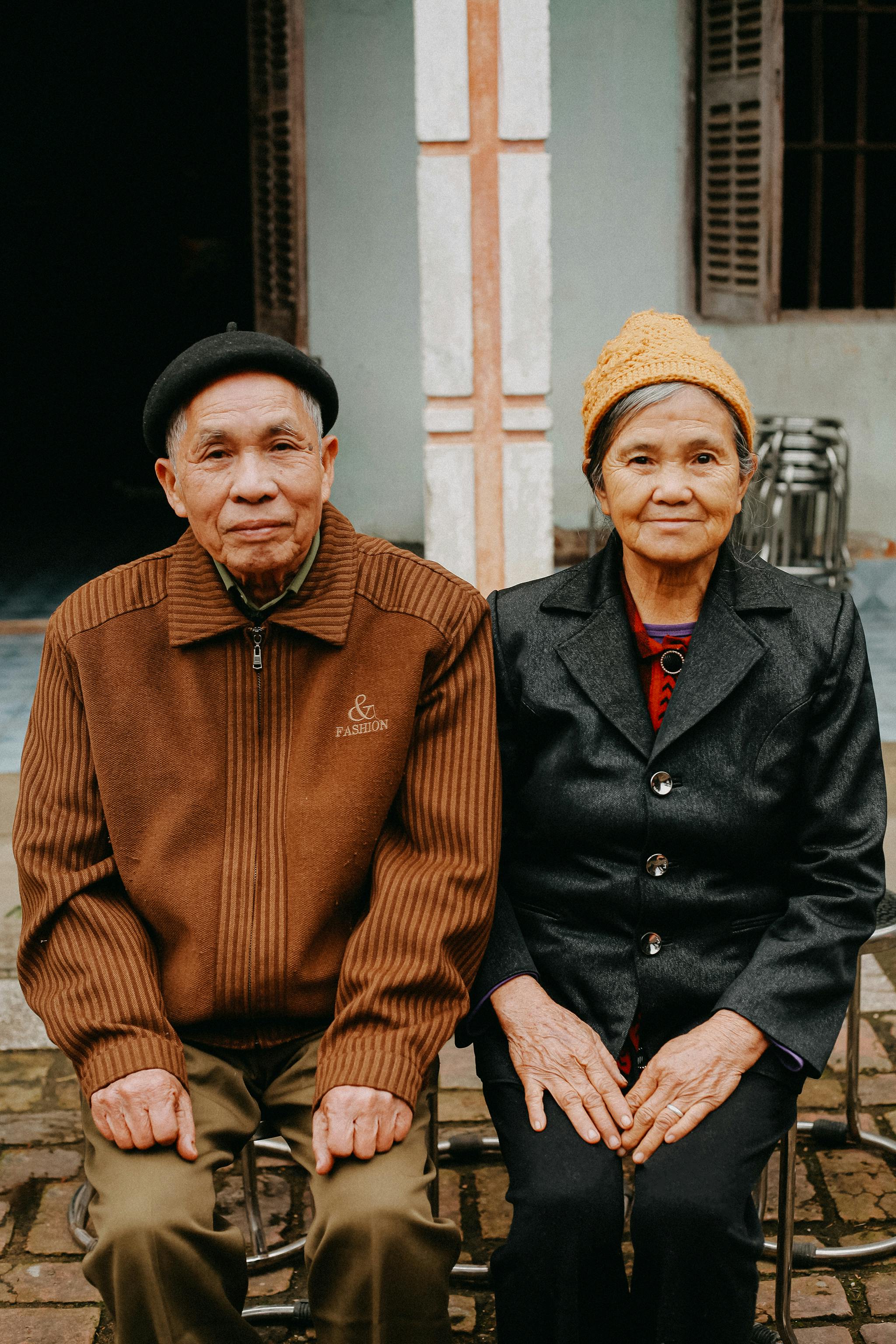 Portrait of a senior couple sitting together outside a house.