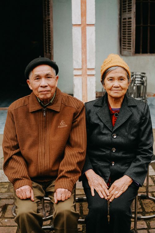 Free Portrait of a senior couple sitting together outside a house. Stock Photo