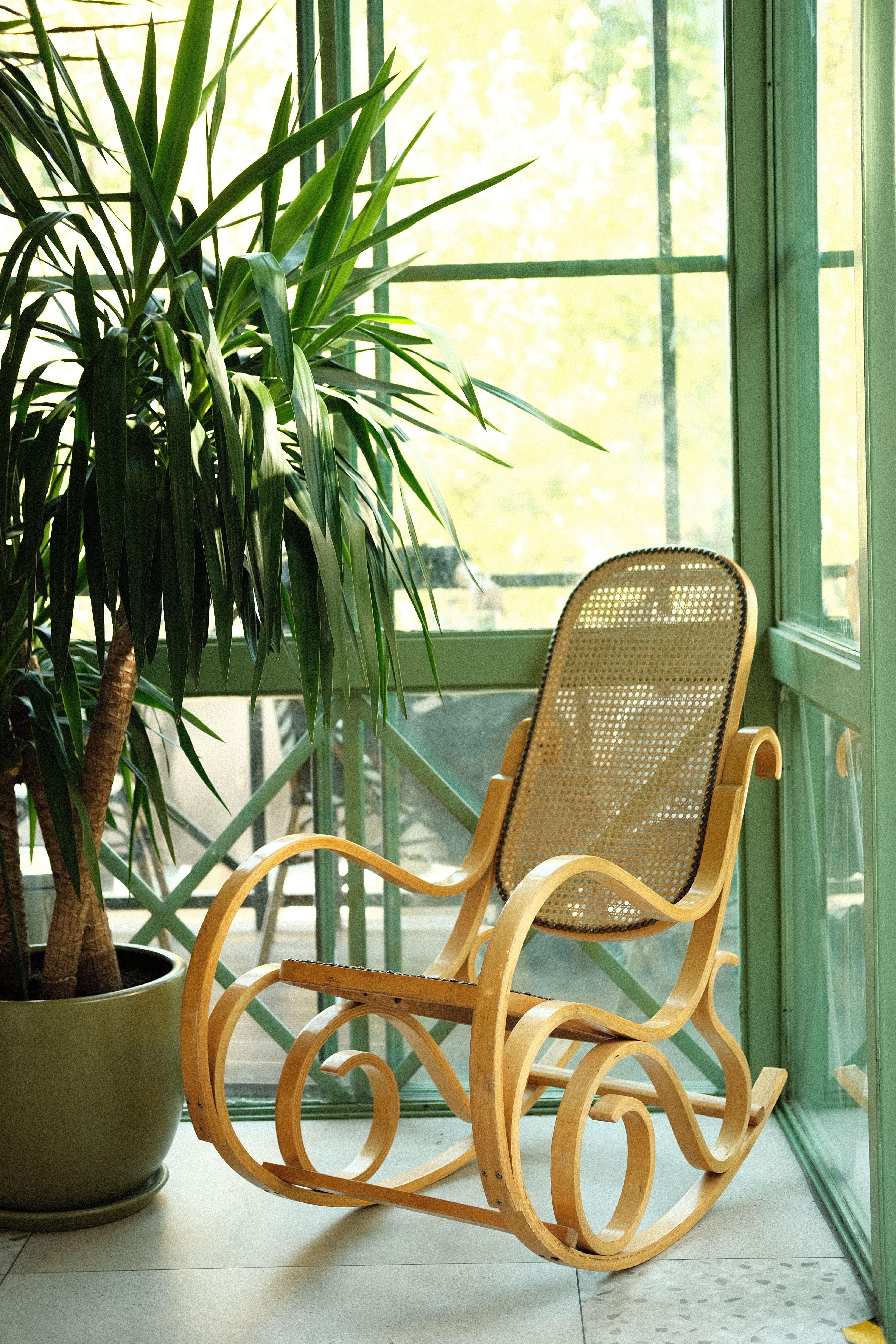 A rocking chair in front of a window with a plant · Free Stock Photo