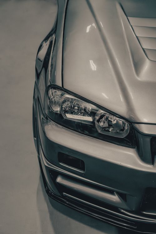 Free Close-up of a sleek silver car with a focus on the headlight design and reflections. Stock Photo