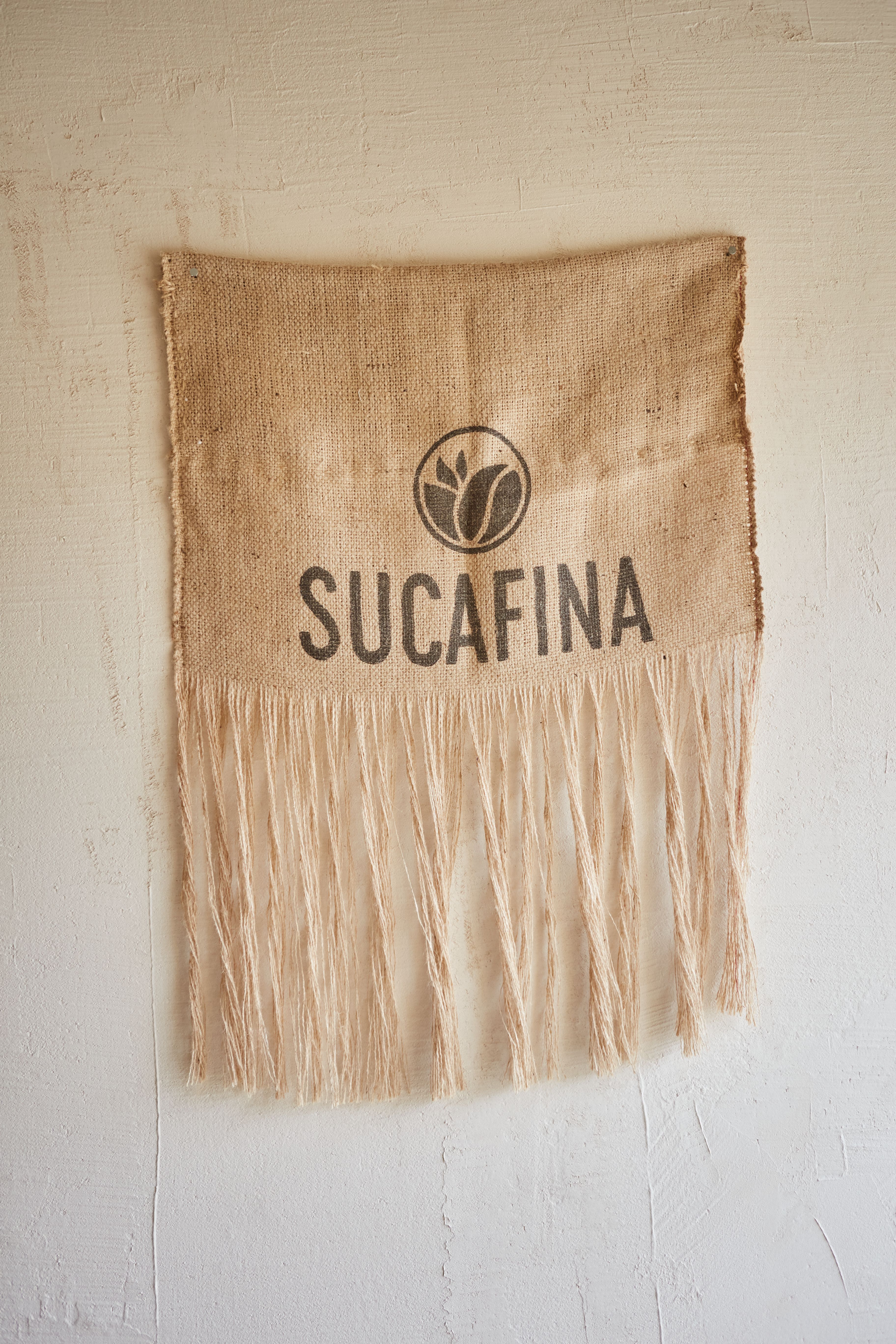 Neutral cotton fringe table runner draped across a boho coffee bar counter with mugs on top