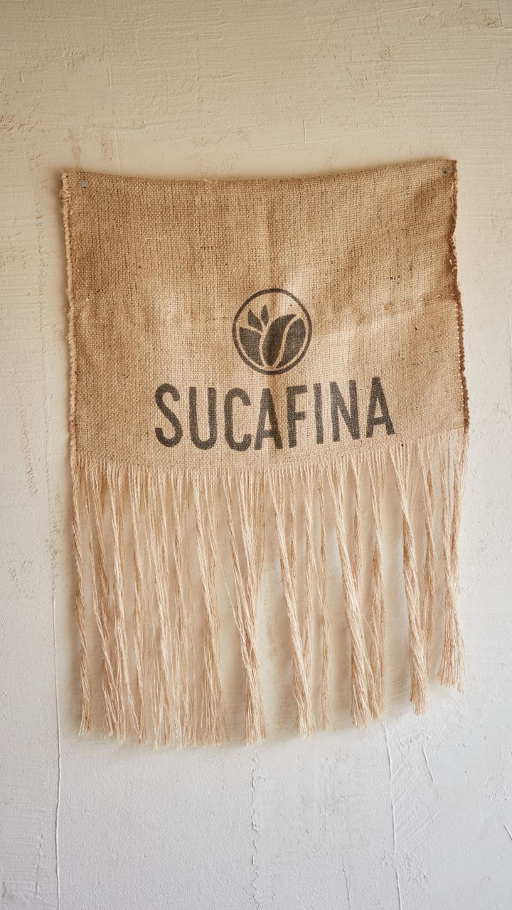 Neutral cotton fringe table runner draped across a boho coffee bar counter with mugs on top