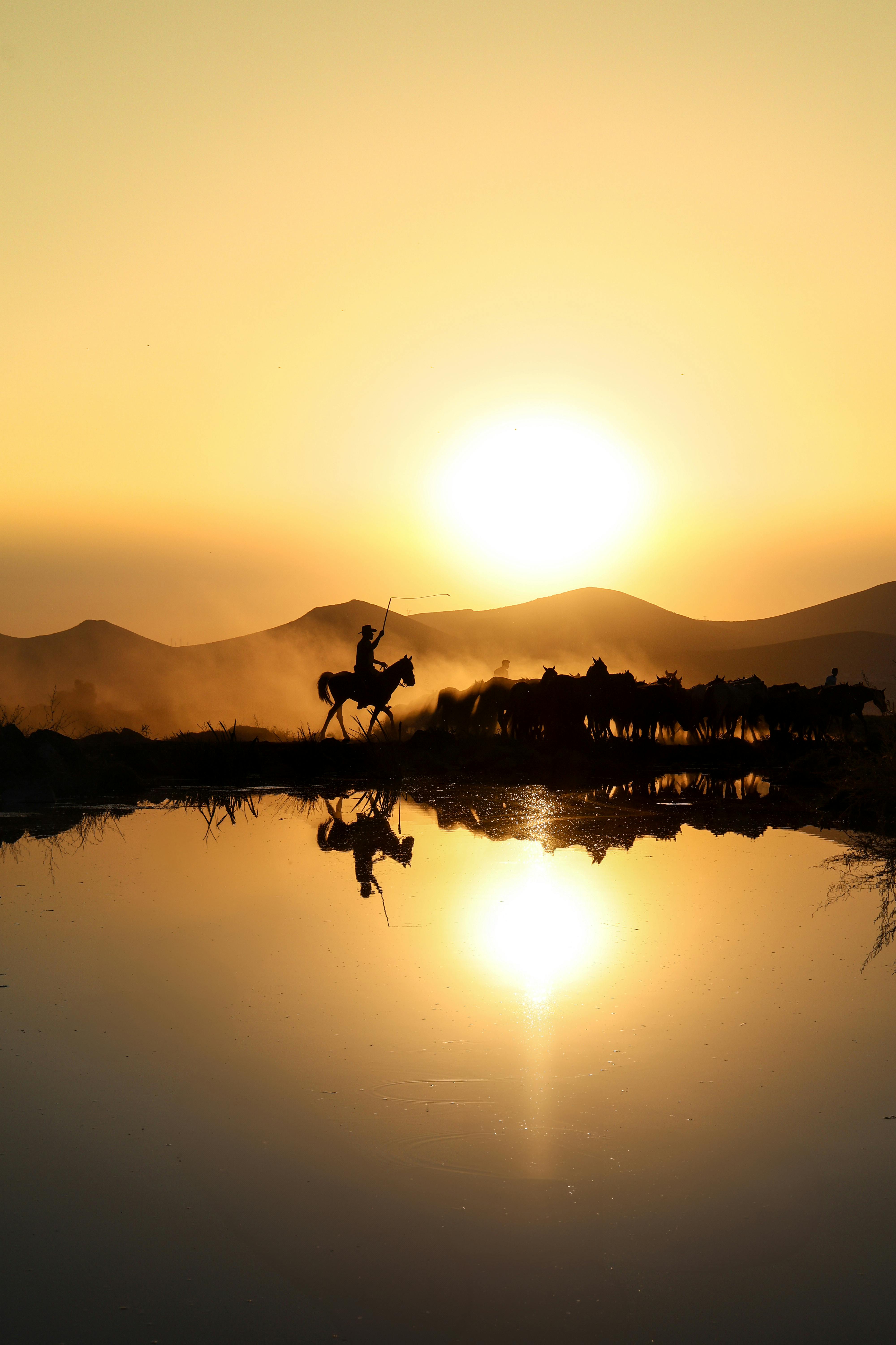 a man riding a horse across a lake at sunset