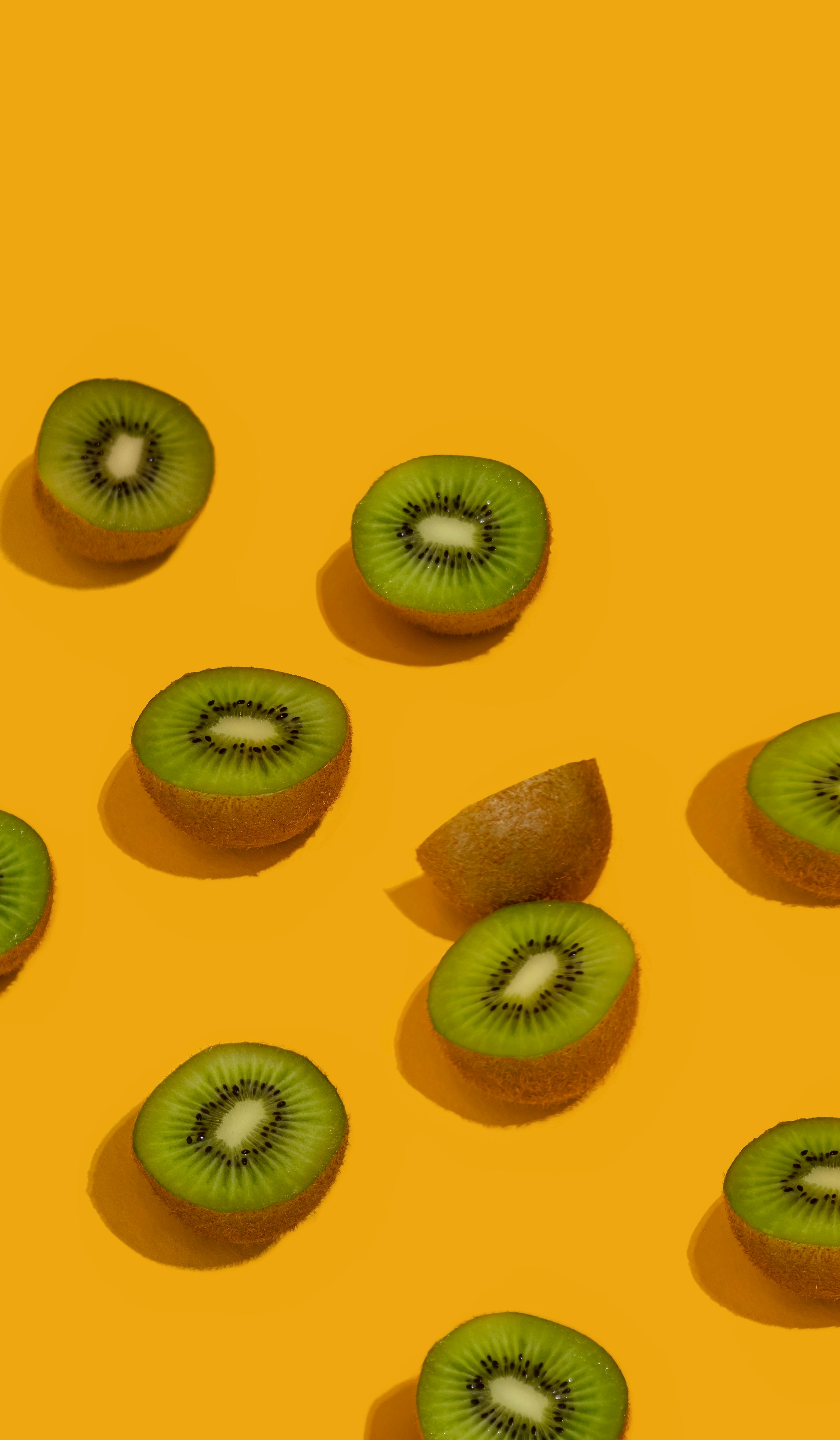 Fresh kiwi slices on a bright yellow background, showcasing health and freshness.