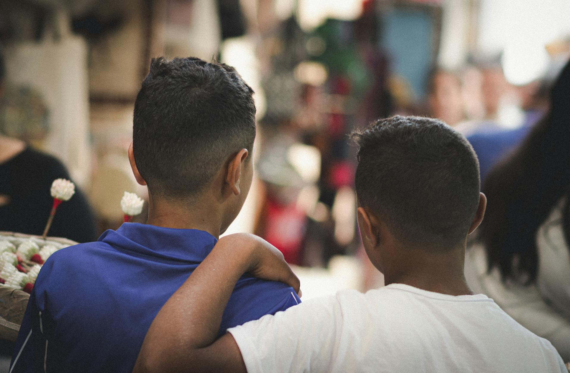 Two boys in Tunis medina sharing a moment of youthful friendship on a bustling street.