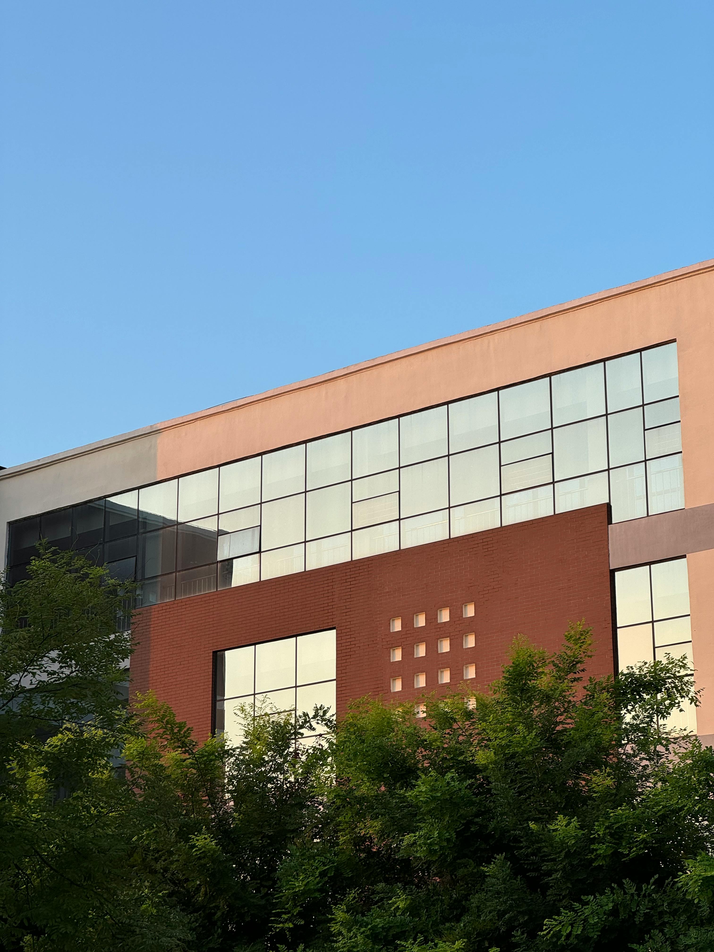 Contemporary glass building with greenery in Dong Li Qu, Tianjin under clear blue sky.