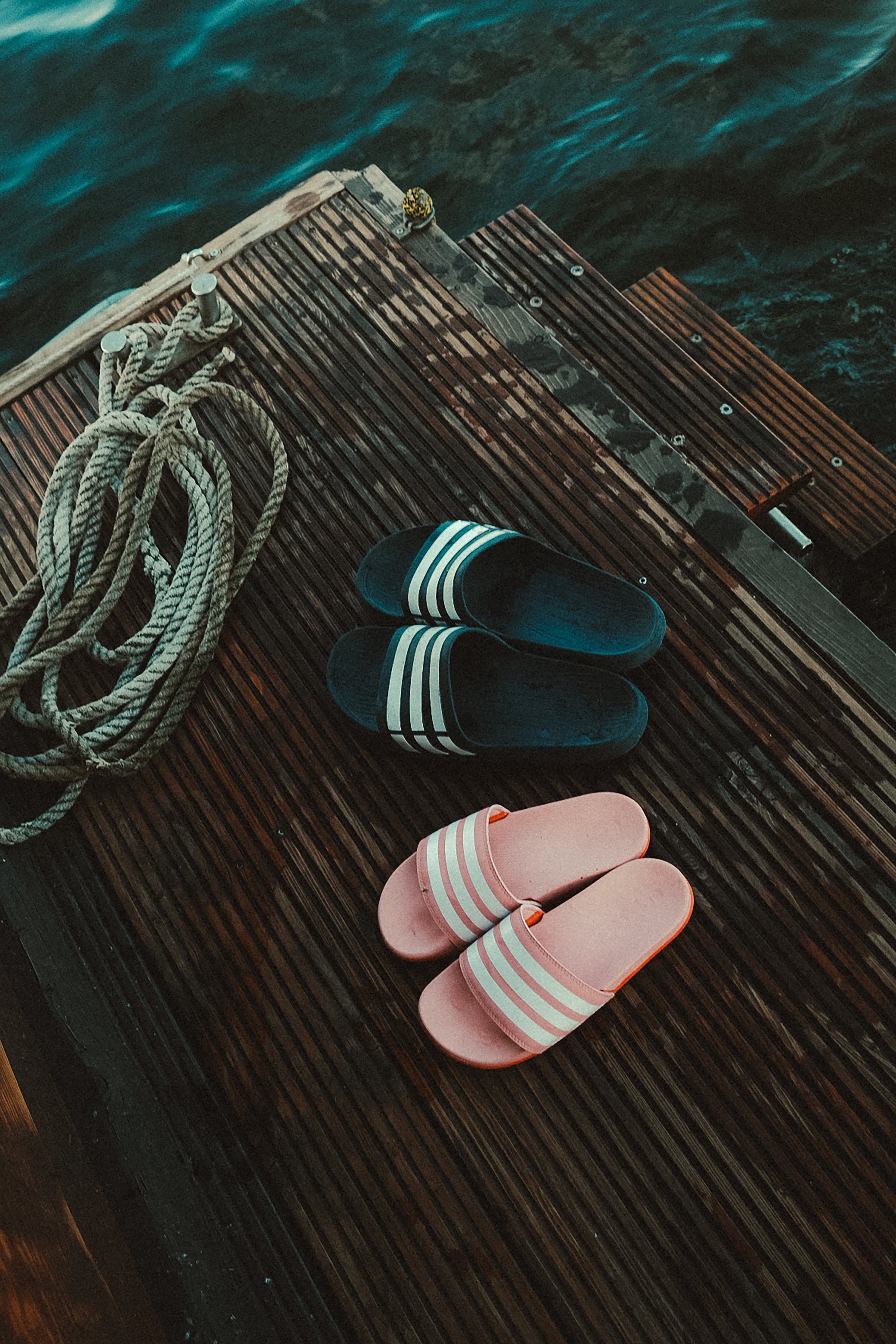 Pair of flip flops on a wooden dock with rope beside water, captured in Wernigerode.