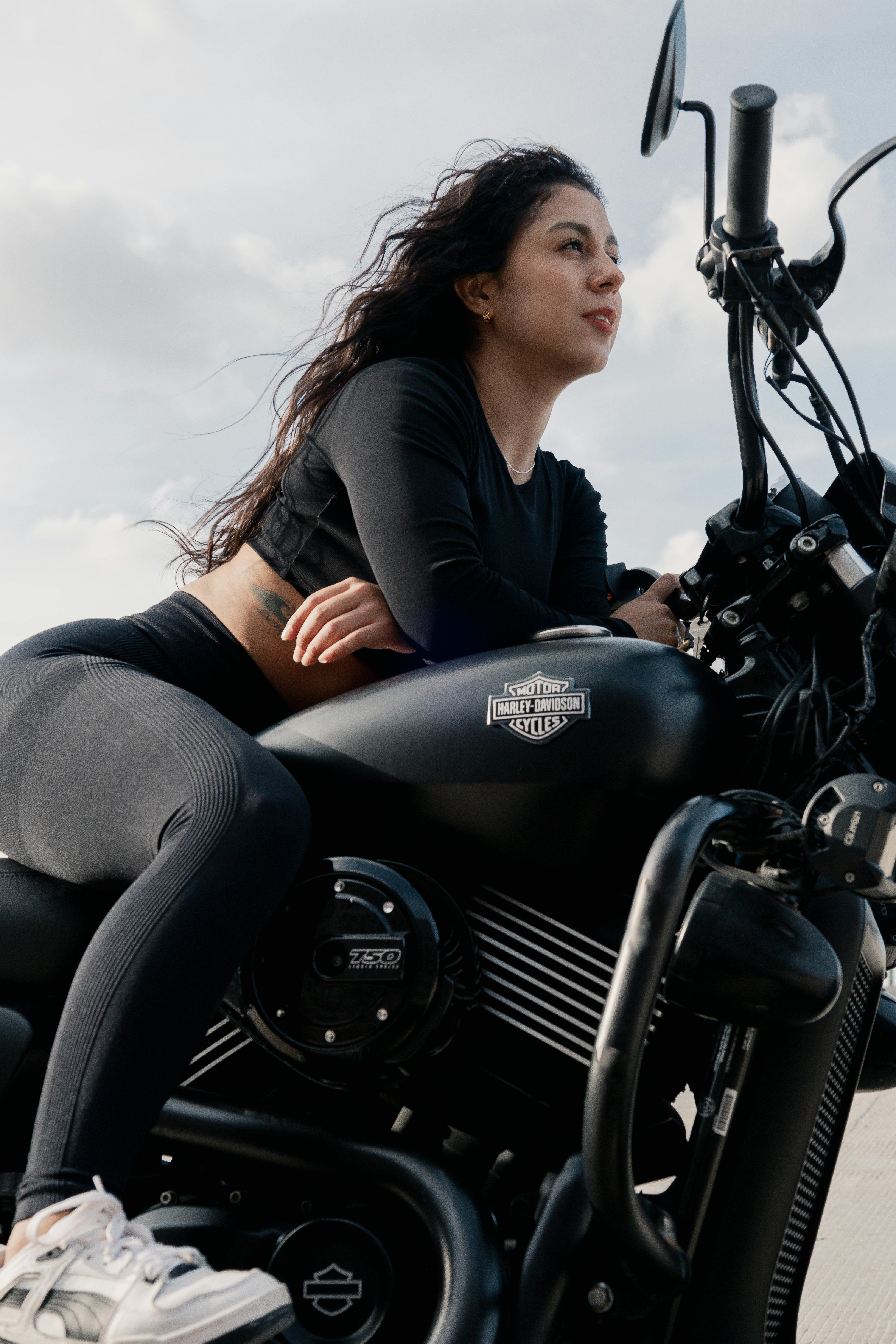 a woman sitting on a motorcycle with her hair up