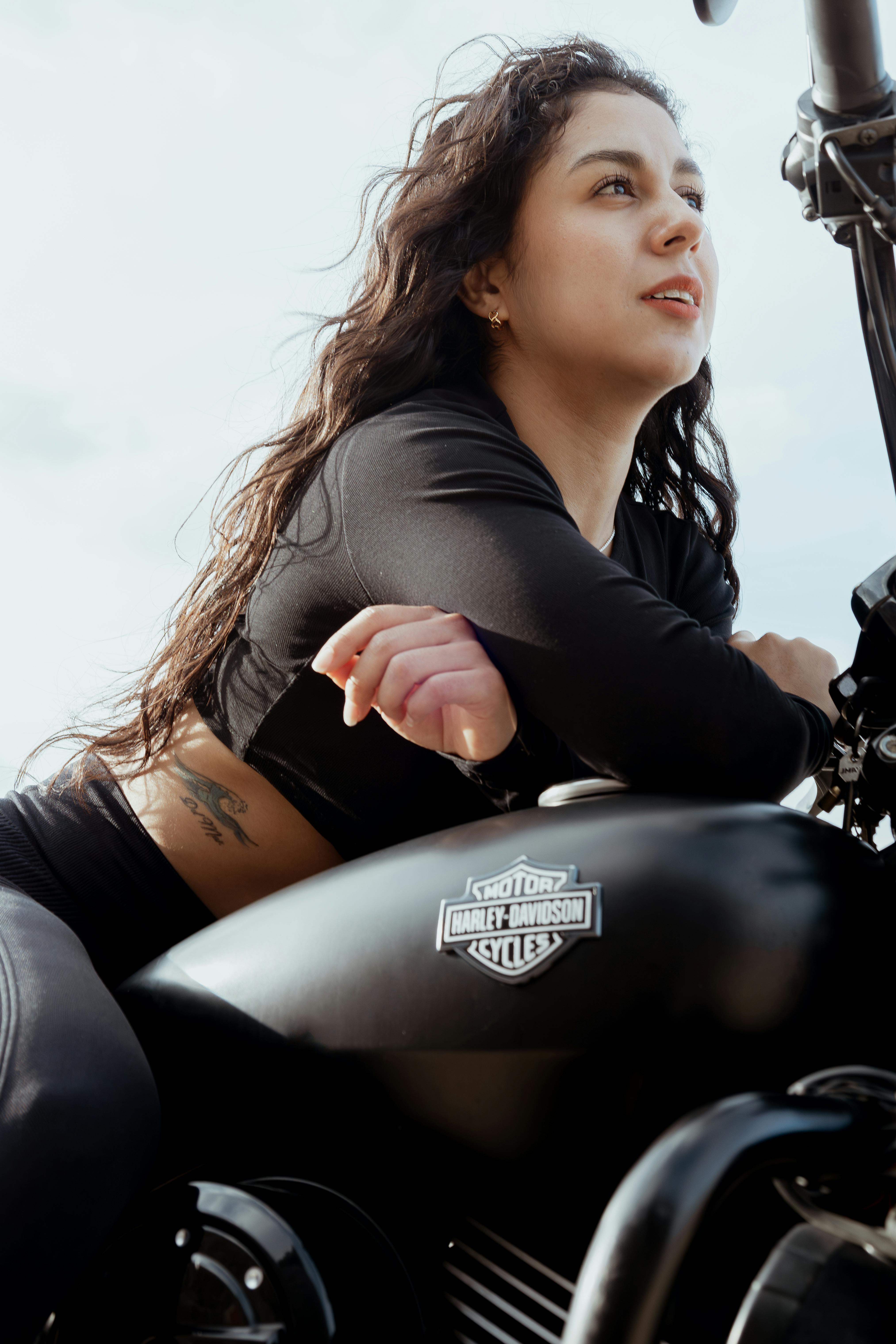 a woman sitting on a motorcycle with her hair up