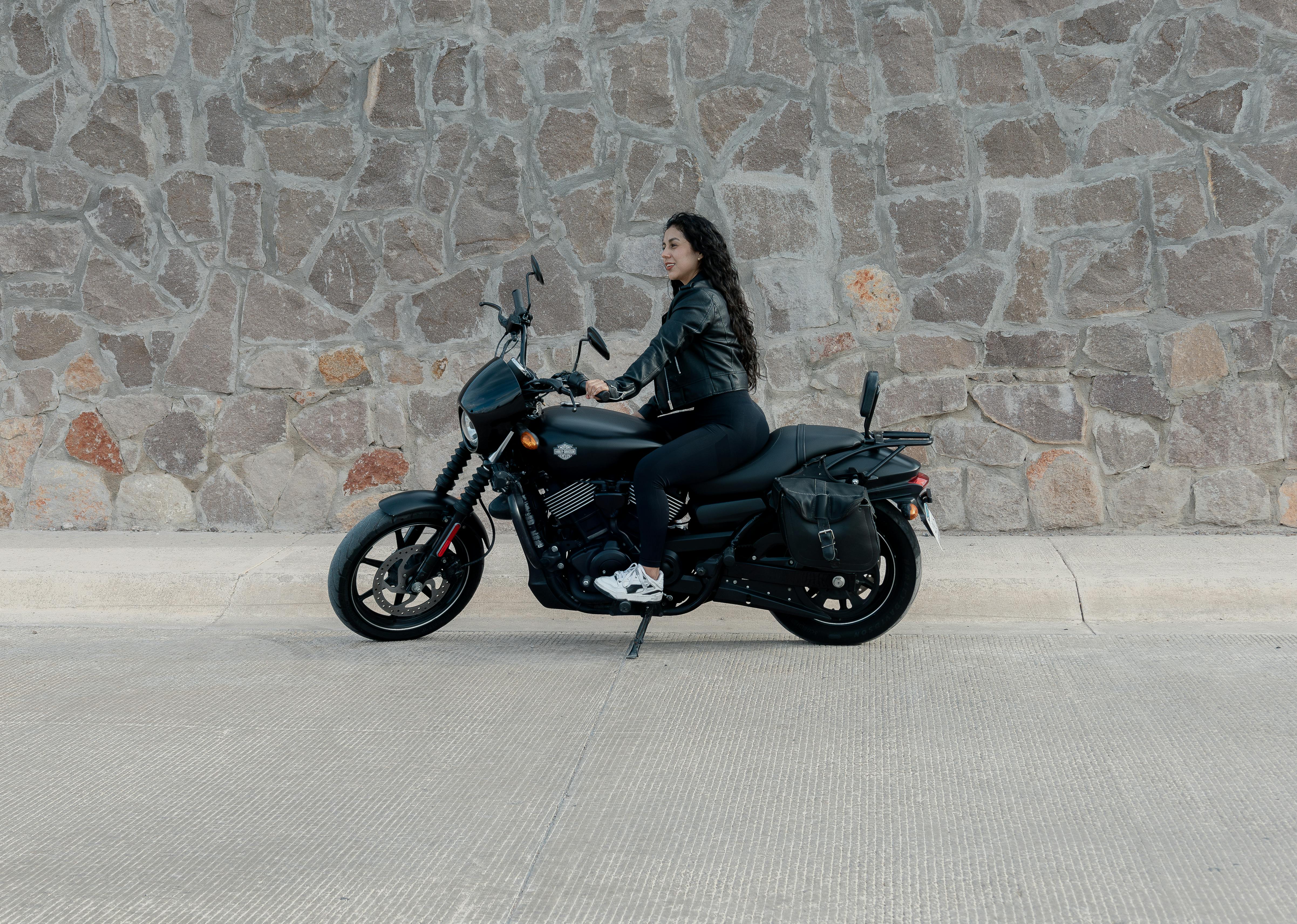 a woman is sitting on a black motorcycle