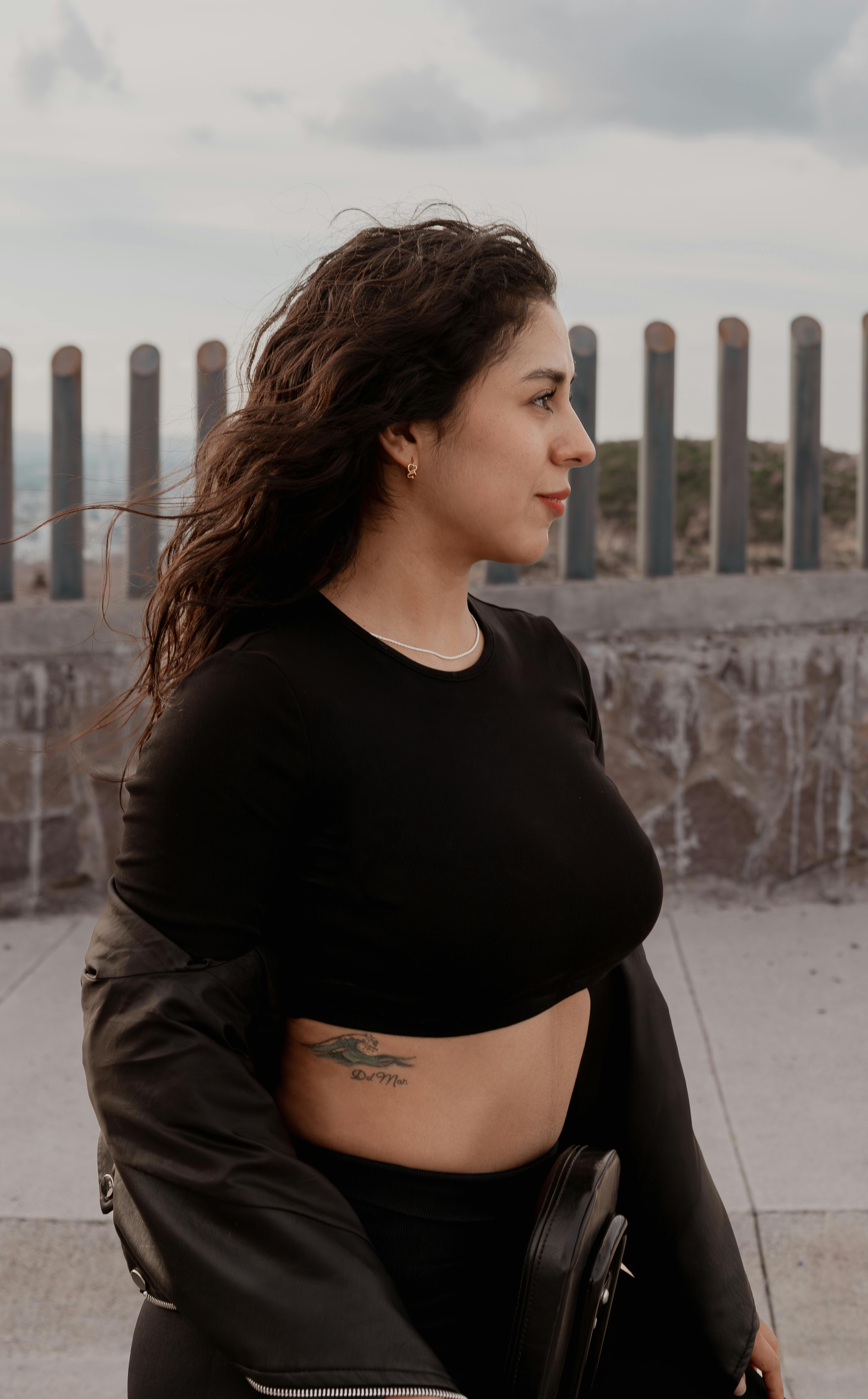 A fashionable woman in a black outfit poses confidently outdoors in San Luis Potosí, Mexico.