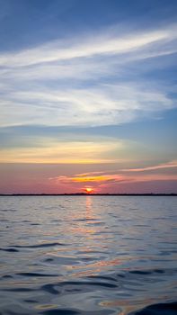 Peaceful sunset over calm ocean waters, capturing vibrant sky hues and tranquil reflections.