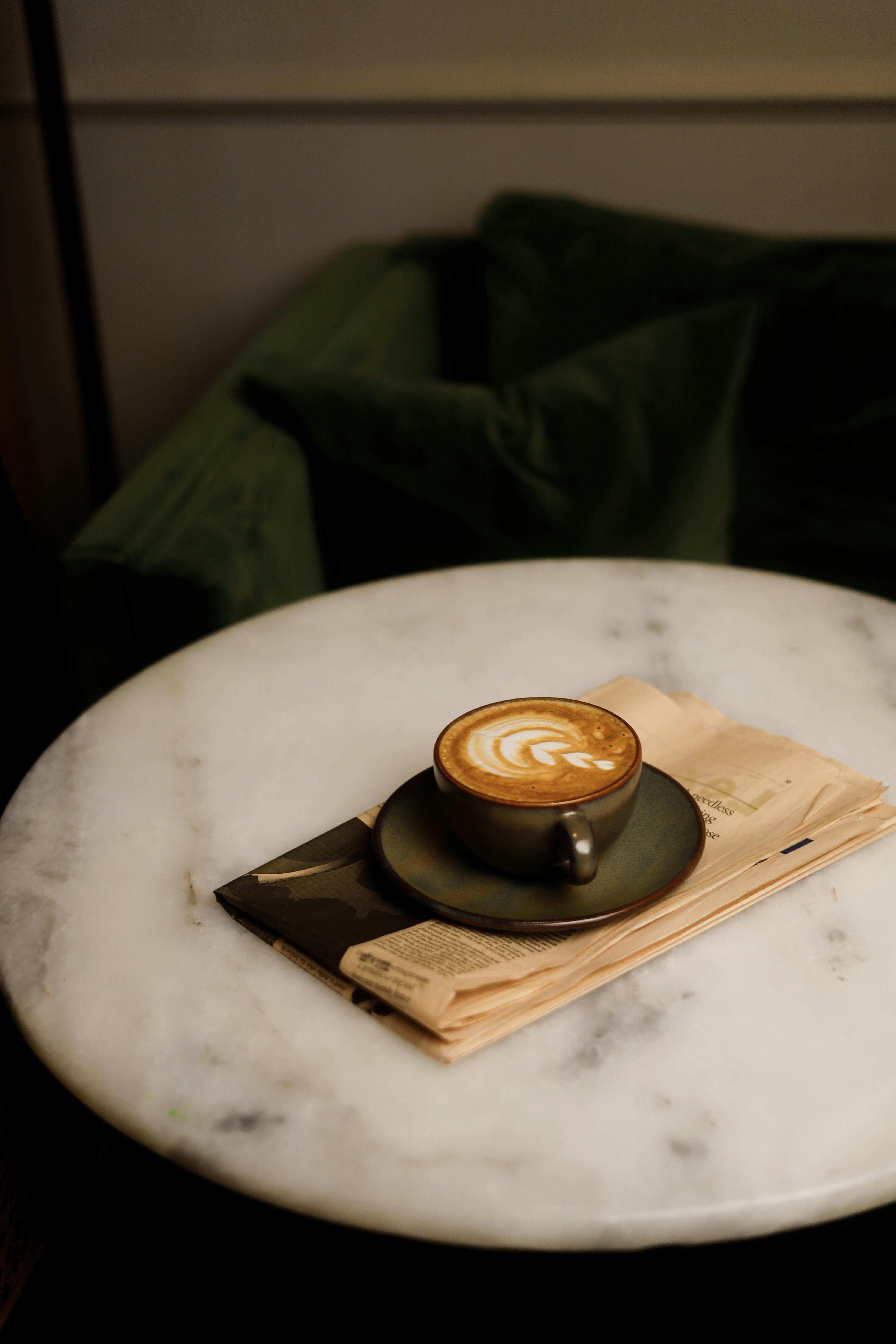 Elegant cup of coffee with latte art on a marble table in warm ambient lighting.