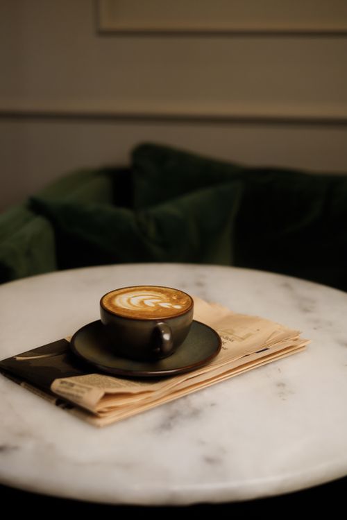 Free Artful latte served in a ceramic cup on a marble table, creating a cozy café ambiance. Stock Photo
