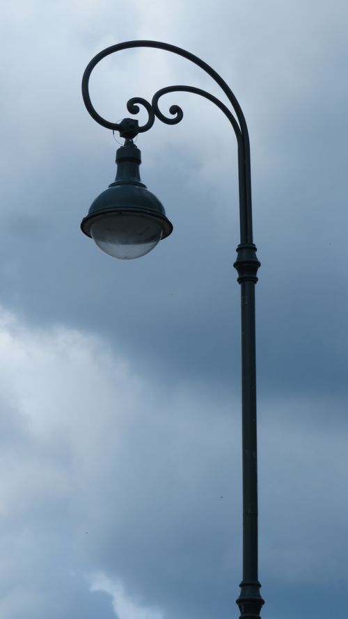 Free A vintage-style street lamp silhouetted against a moody, overcast sky, highlighting contrast. Stock Photo