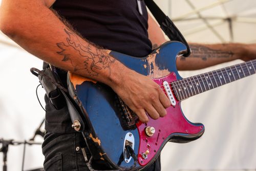 Free Close-up of a guitarist playing an electric guitar at an outdoor rock concert. Stock Photo