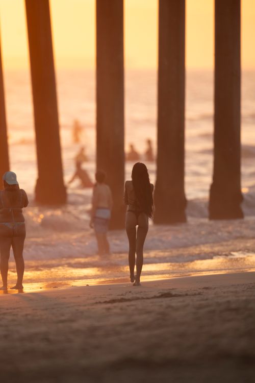 A woman walking on the beach at sunset · Free Stock Photo