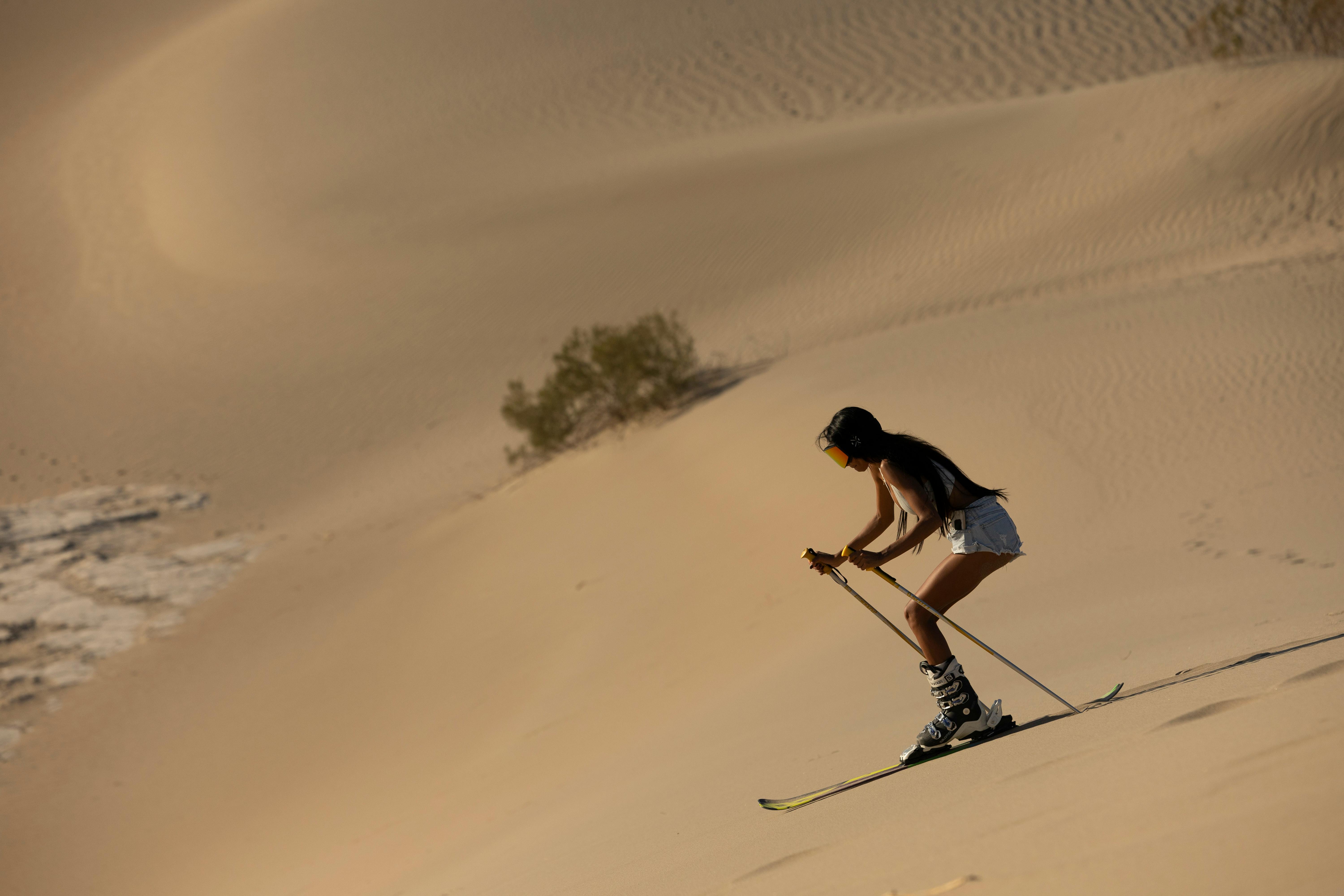 A woman skiing on desert sand dunes, showcasing adventure and uniqueness.