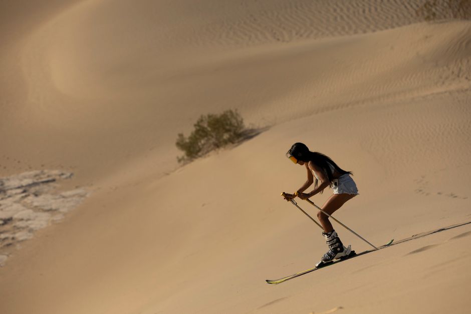 A woman skiing on desert sand dunes, showcasing adventure and uniqueness.