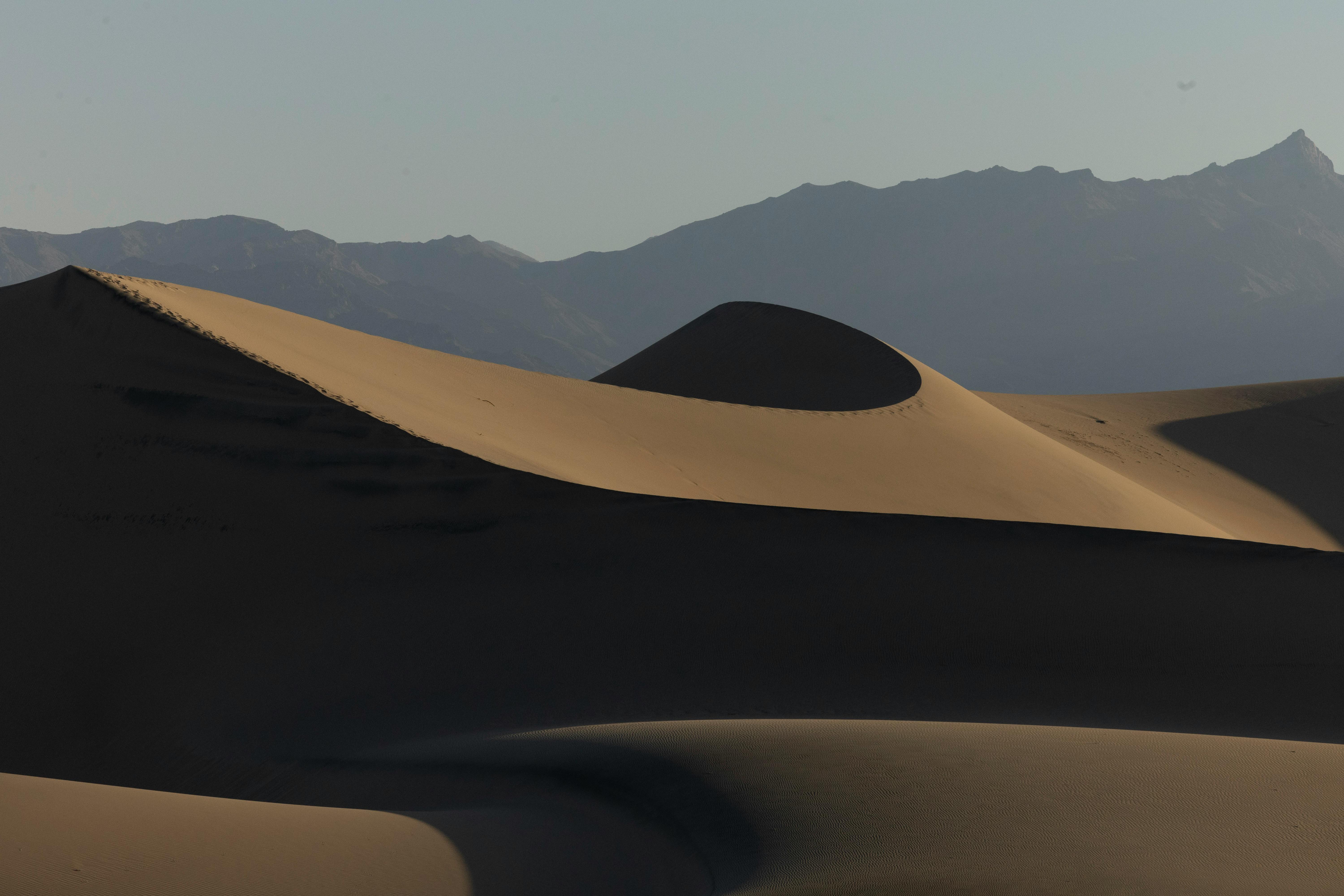 a sand dune with mountains in the background