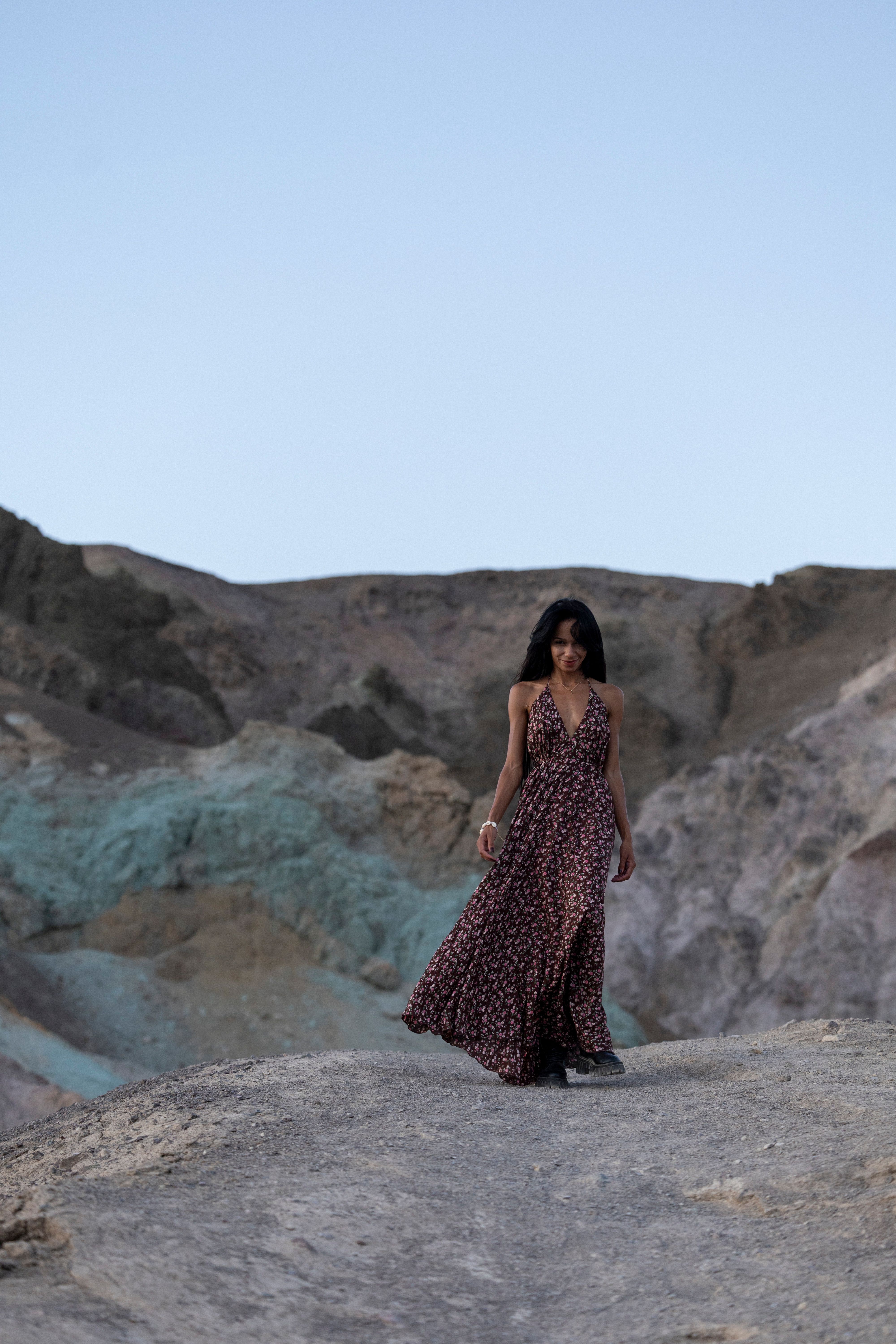 A woman in a long dress walking on a rocky terrain · Free Stock Photo