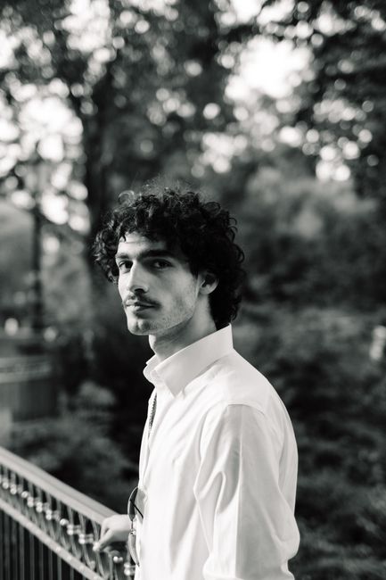Black and white portrait of a young man standing outdoors in Düsseldorf.