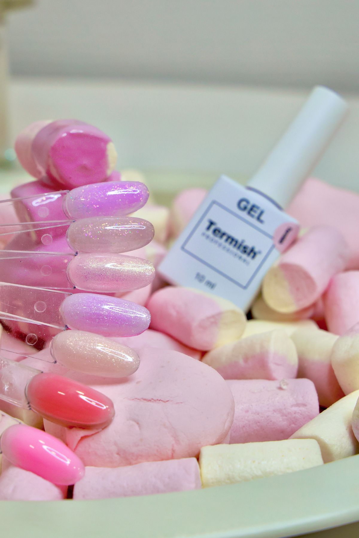 Pink and glittery nail polish samples displayed on marshmallows, perfect for beauty themes.