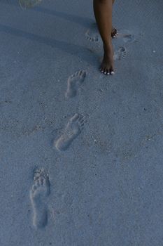 A serene capture of footsteps in the sand with a person walking on a beach in Lagos, Nigeria.