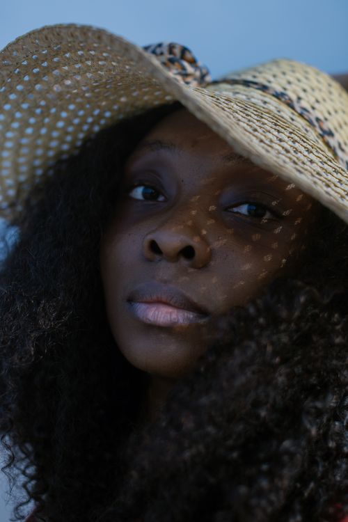Free A striking portrait of a woman wearing a sun hat with unique lighting through the weave. Stock Photo