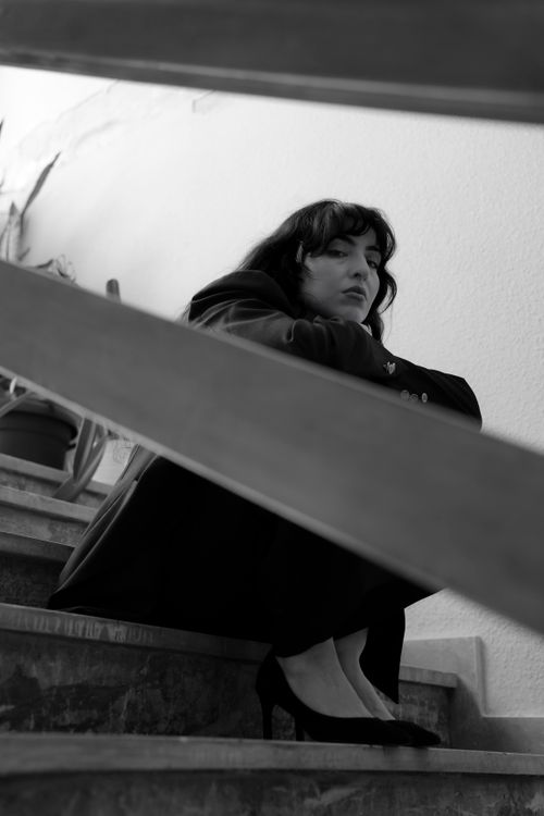 Free Black and white portrait of a woman seated on stairs, conveying contemplation and mystery. Stock Photo
