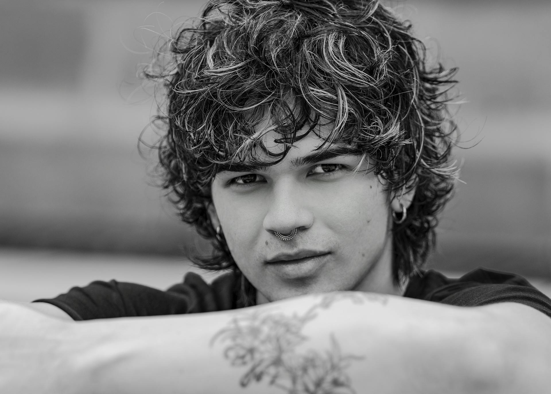 Artistic black and white portrait of a young adult with curly hair and septum piercing in San José, Costa Rica.